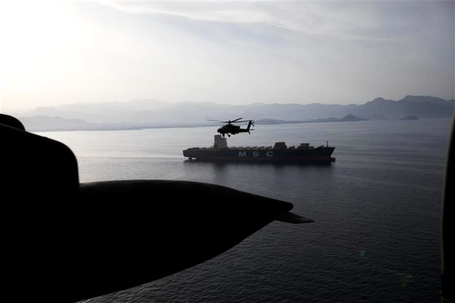 US Army AH-64 Apache helicopters fly over merchant ships in the Strait of Hormuz