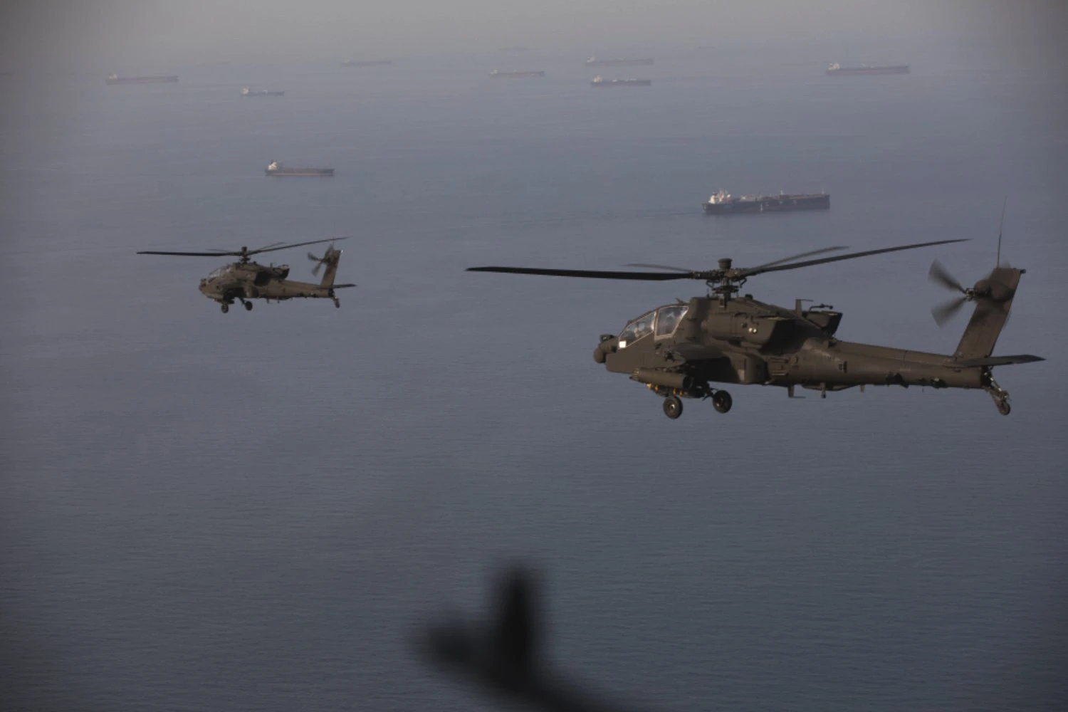 US Army AH-64 Apache helicopters fly over merchant ships in the Strait of Hormuz | CENTCOM